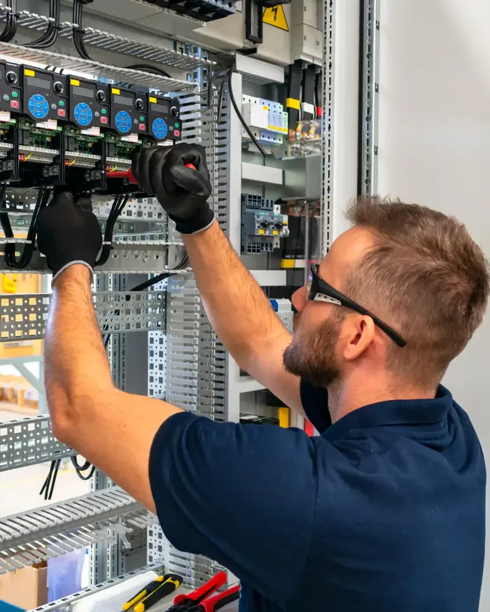 Elektriker arbeitet an einem elektrischen Schaltschrank.
